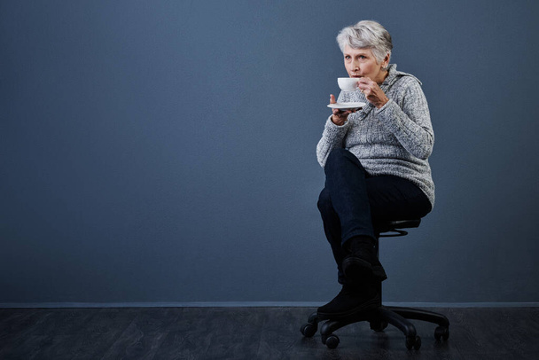 Ich kann das den ganzen Tag machen. Studioaufnahme einer älteren Frau, die sich hinsetzt und allein eine Tasse Tee genießt - Foto, Bild