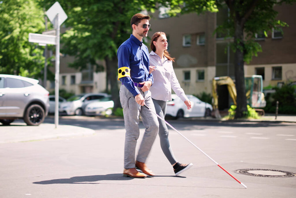 Young Woman Helping Blind Man With White Stick While Crossing Road - Valokuva, kuva