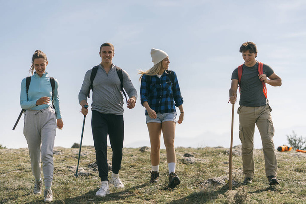 Vier Freunde lächeln und wandern auf dem Gipfel des Berges - Foto, Bild