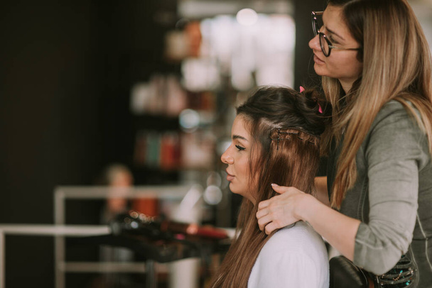Brunette hair stylist making her client hair - Valokuva, kuva