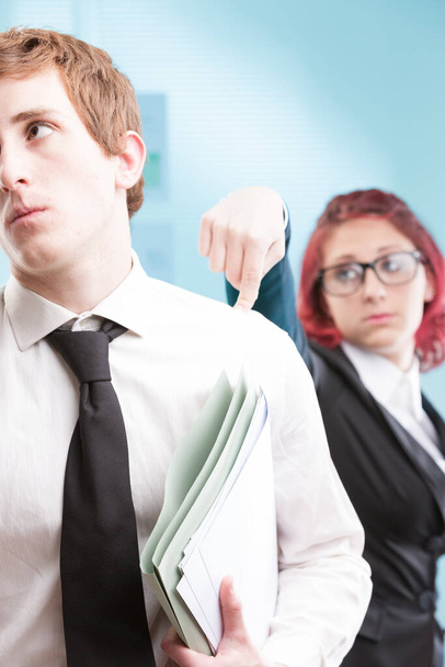 Bántalmazó viselkedés: egy nő féktelen haragot mutat egy férfi kollégája iránt. Egészségtelen munkahelyi környezet - Fotó, kép