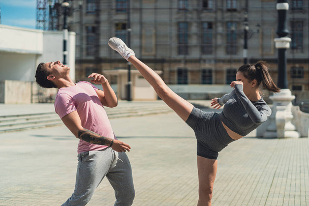 Flexible kickboxer femenino patear a su amigo masculino en una cabeza con su pierna - Foto, Imagen