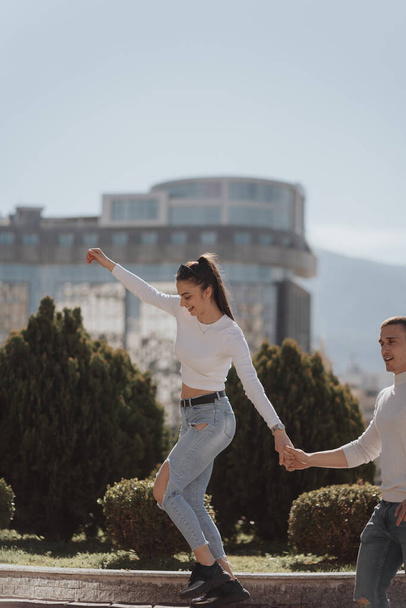 Beautiful girl with ponytail smiling and walking while holding her boyfriend - Fotó, kép