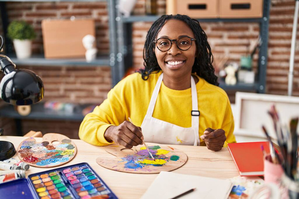 Αφρο-αμερικανίδα καλλιτέχνης χαμογελώντας αυτοπεποίθηση ανάμειξη χρώμα στο στούντιο τέχνης - Φωτογραφία, εικόνα