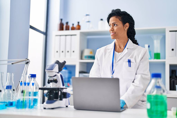 Mujer afroamericana vistiendo uniforme científico usando laptop en laboratorio - Foto, imagen
