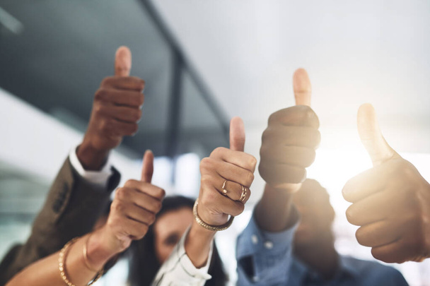You should be proud of your achievements. Closeup shot of a group of businesspeople showing thumbs up in an office - Photo, Image