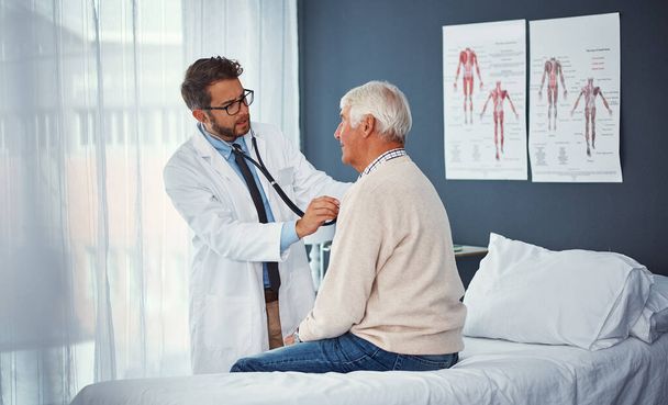 Regelmatige controles zijn essentieel voor senioren. een arts die een senior patiënt met een stethoscoop onderzoekt in een kliniek - Foto, afbeelding