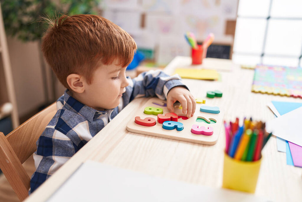 Imádnivaló kisbaba játszik matek puzzle játék ül az asztalon az osztályteremben - Fotó, kép