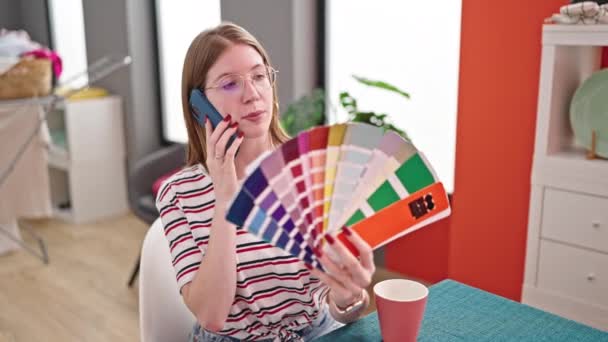 Νεαρή ξανθιά γυναίκα μιλάει στο smartphone επιλέγοντας χρώμα μπογιάς στην τραπεζαρία - Πλάνα, βίντεο