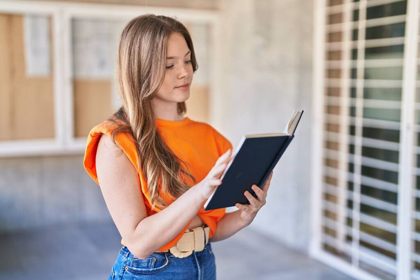 Młoda kobieta czyta książkę na uniwersytecie - Zdjęcie, obraz