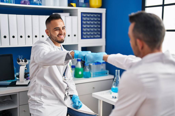 Dva muži vědci se usmívají sebevědomě hrbolaté pěsti v laboratoři - Fotografie, Obrázek