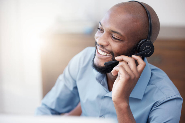 Call center, black man and happy agent working on computer in the office, business in telemarketing or customer service. Businessman, face with smile and crm, conversation with client on help desk. - Фото, изображение