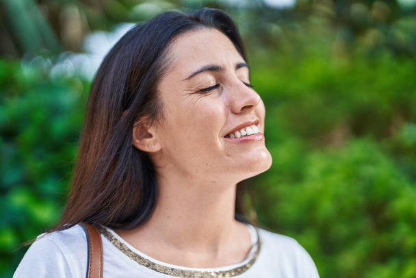 Young beautiful hispanic woman breathing with closed eyes at park - Photo, Image