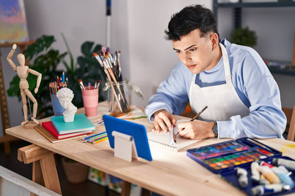 Young non binary man artist using touchpad drawing on notebook at art studio - Photo, Image