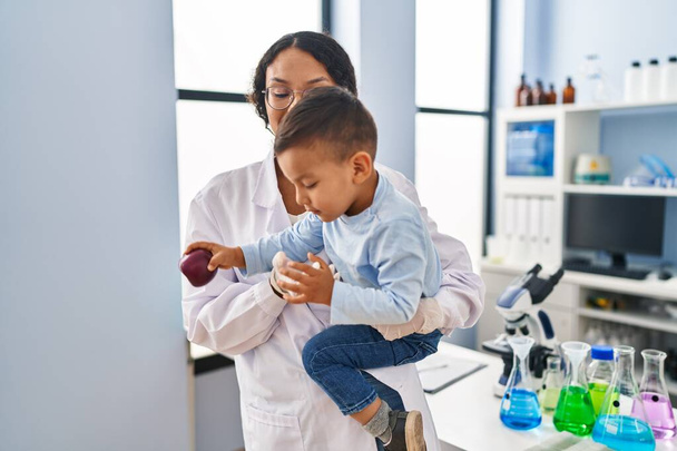 Madre e hijo vistiendo uniforme científico abrazándose en el laboratorio - Foto, Imagen