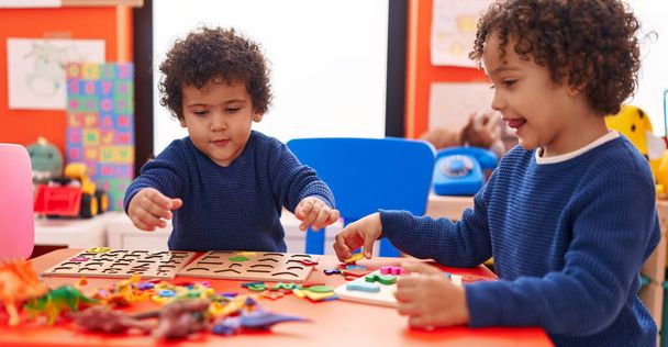 Adoráveis meninos afro-americanos brincando com matemática jogo de quebra-cabeça sentado na mesa no jardim de infância - Foto, Imagem