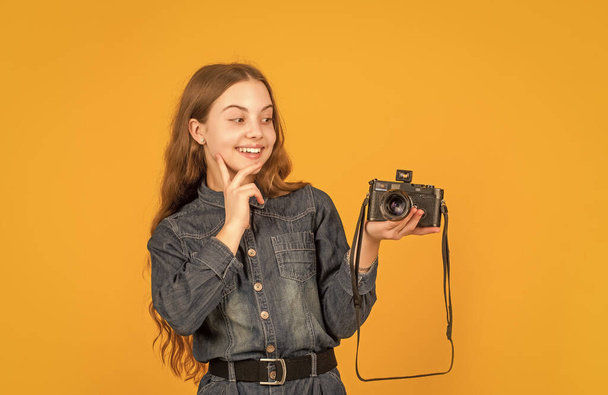 Interested in photography. Happy child looking at photo camera on hand. Girl photographer with camera. - Foto, Imagen