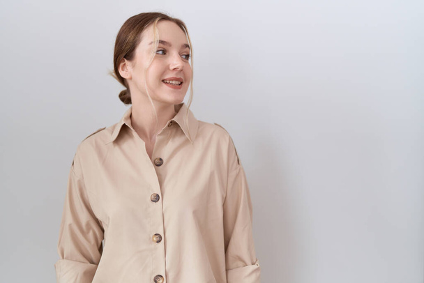Jonge blanke vrouw draagt casual shirt en kijkt weg met een glimlach op haar gezicht, natuurlijke expressie. lachen vol vertrouwen.  - Foto, afbeelding