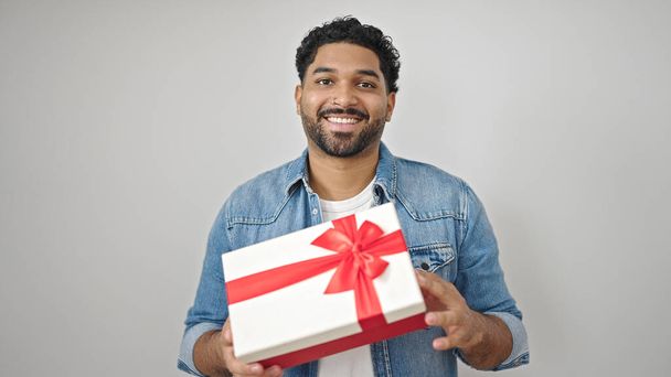 Africain américain souriant confiant tenant cadeau sur fond blanc isolé - Photo, image