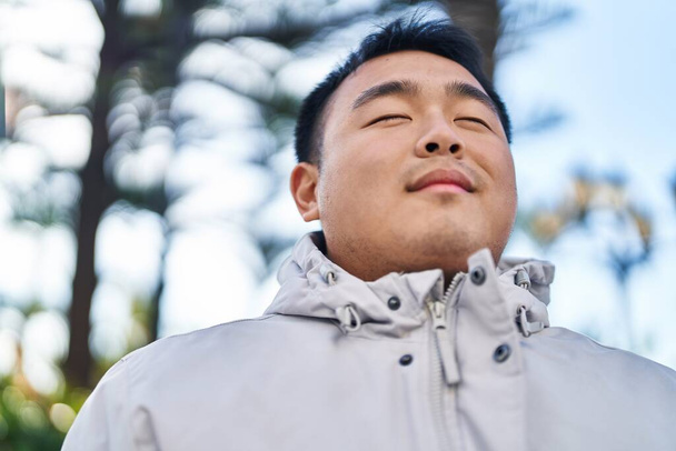 Nuori kiinalainen mies hengitys seisoo puistossa - Valokuva, kuva