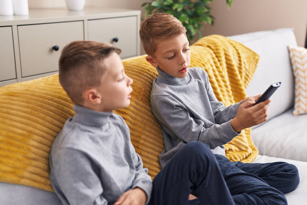 Uroczy chłopcy oglądanie telewizji siedzi na kanapie w domu - Zdjęcie, obraz