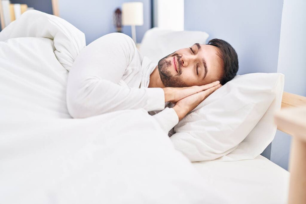 Giovane uomo ispanico sdraiato sul letto a dormire in camera da letto - Foto, immagini