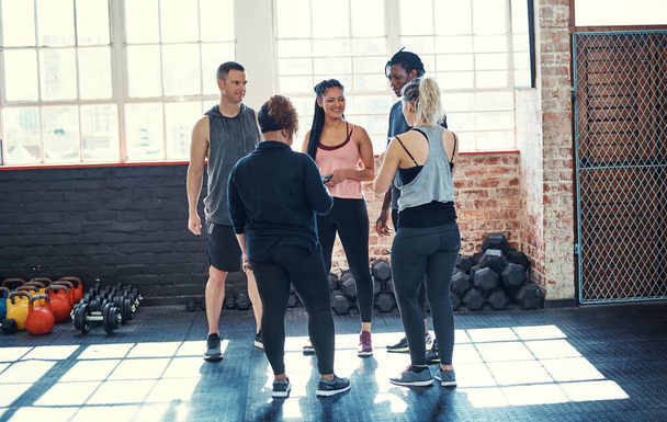 Mindenki alakítson egy kört. egy vidám fiatal csoport, akik egy körben állnak és beszélgetnek edzés előtt egy edzőteremben. - Fotó, kép