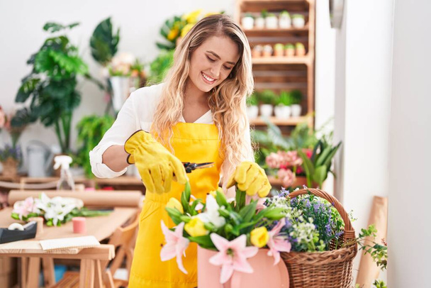 Young blonde woman florist cutting plant at florist - Photo, Image