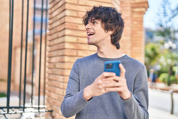 Νέοι ισπανόφωνοι χαμογελώντας αυτοπεποίθηση χρησιμοποιώντας smartphone στο δρόμο - Φωτογραφία, εικόνα