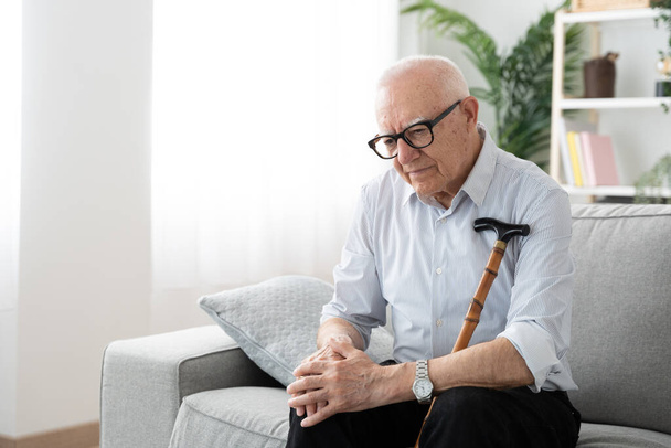 Elderly man suffering knee pain. Mature person sitting on sofa. - Photo, Image