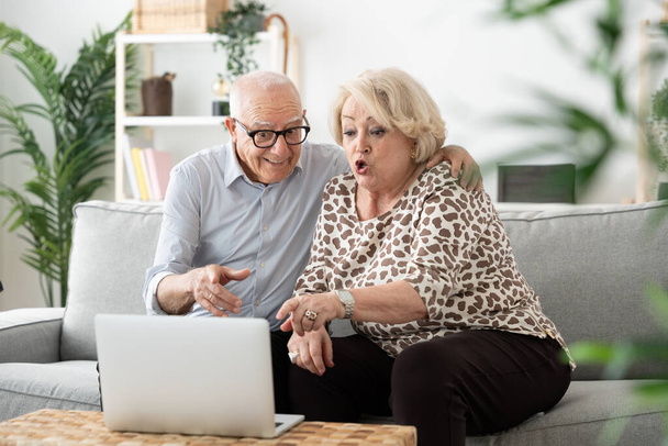 Пожилая пара с видеозвонком на ноутбуке. Взрослый мужчина и женщина, использующие технологии - Фото, изображение