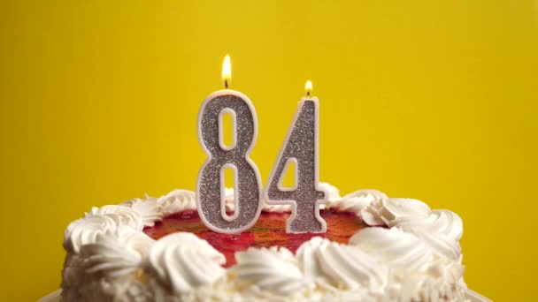 Una vela en la forma del número 84, atascada en un pastel de vacaciones, se apaga. Celebrar un cumpleaños o un evento histórico. El clímax de la celebración. - Metraje, vídeo