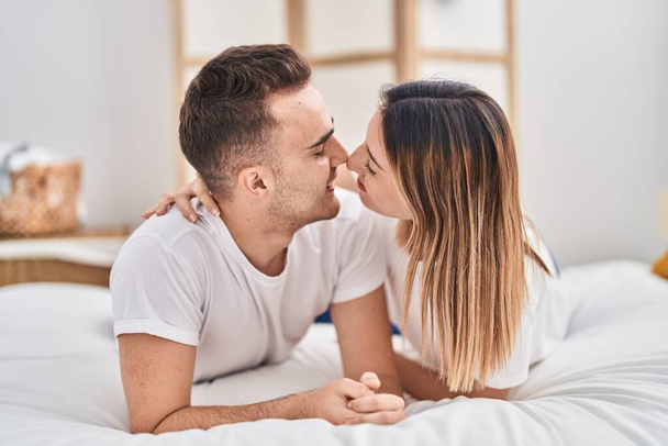 Άνδρες και γυναίκες ξαπλωμένοι στο κρεβάτι αγκαλιασμένοι και φιλιούνται στην κρεβατοκάμαρα. - Φωτογραφία, εικόνα