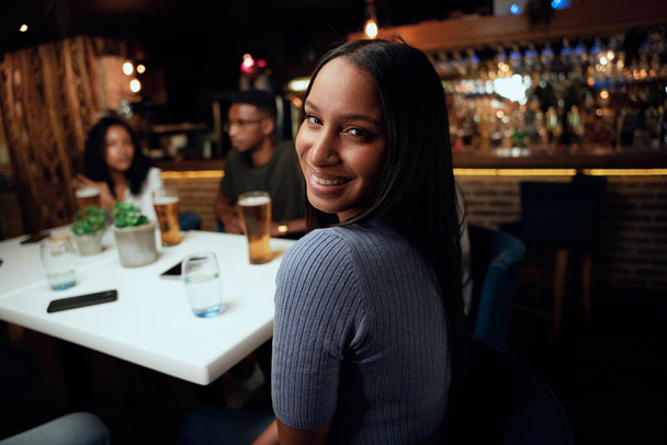 Happy young multiracial group of friends wearing casual clothing smiling and talking while celebrating at bar - Foto, afbeelding