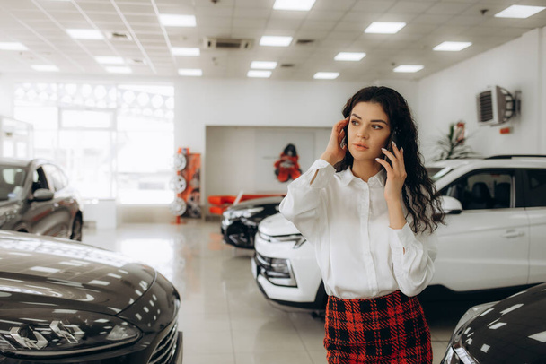 Mujer de negocios hablando por teléfono por el coche en una sala de exposición de coches - Foto, Imagen