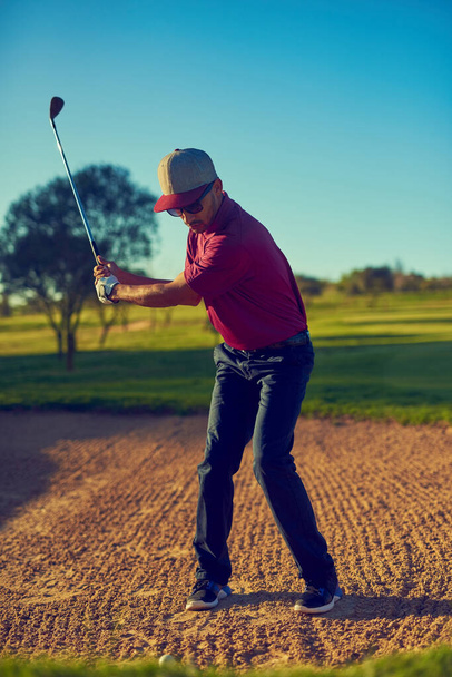 Top, sığınağa karşı. Genç bir adam golf raundunda sığınaktan topa vuruyor. - Fotoğraf, Görsel