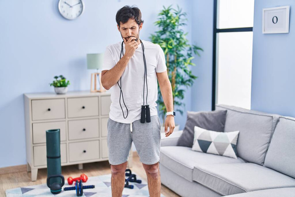 Handsome latin man wearing sportswear at home feeling unwell and coughing as symptom for cold or bronchitis. health care concept.  - Photo, Image