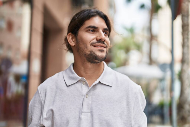 Young hispanic man smiling confident looking to the side at street - Photo, Image