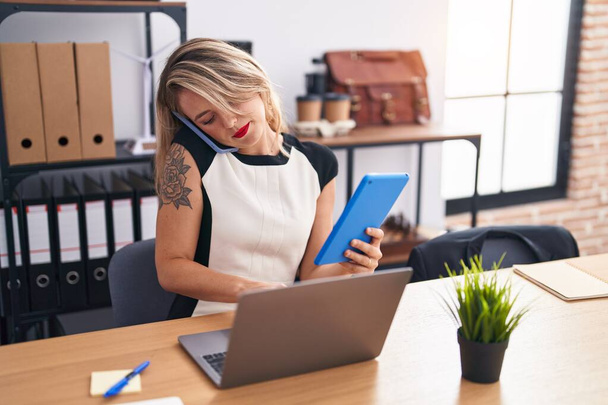 Jovem bela mulher hispânica empresária falando no smartphone usando touchpad no escritório - Foto, Imagem