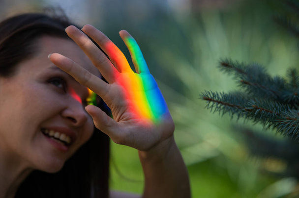 Portrait of caucasian woman with rainbow beam on her face outdoors - Fotó, kép