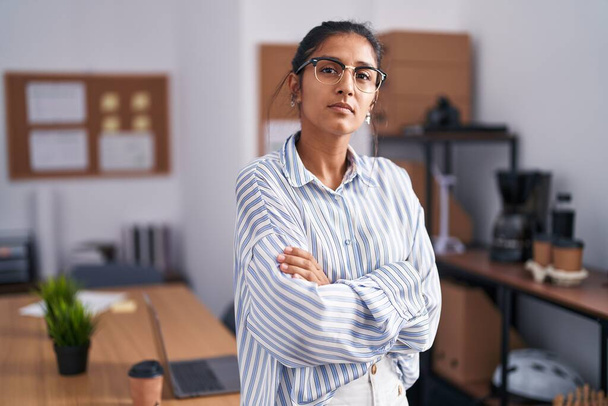 Young beautiful hispanic woman business worker standing with arms crossed gesture at office - Foto, Imagen