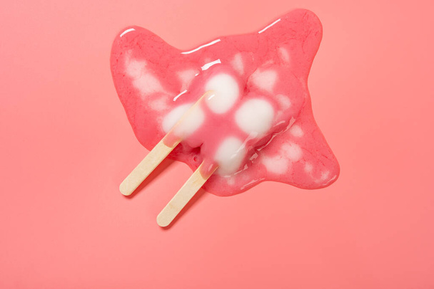 top view half melted butterfly shape popsicle on pink background - Foto, imagen