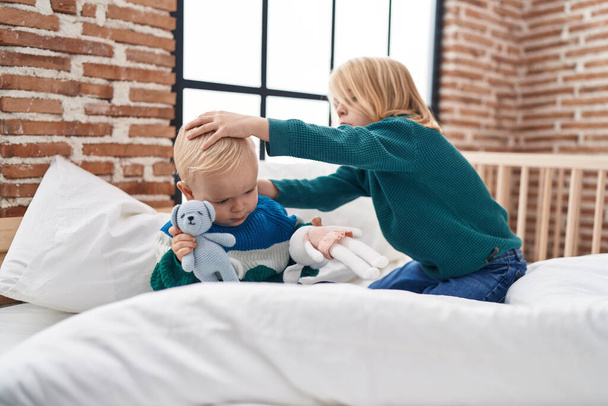 Sevimli bir çocuk ve kız yatak odasında oyuncak ayıyla oynuyorlar. - Fotoğraf, Görsel