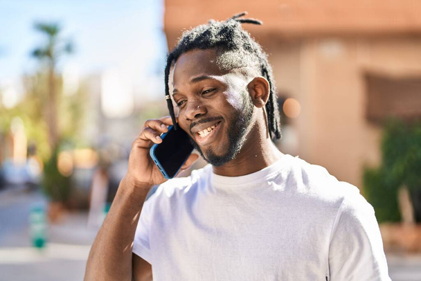 Африканская американка улыбается уверенно разговаривая по смартфону на улице - Фото, изображение