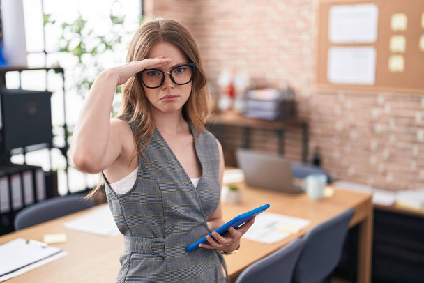 Καυκάσια γυναίκα που εργάζεται στο γραφείο φορώντας γυαλιά ανησυχούν και τόνισε για ένα πρόβλημα με το χέρι στο μέτωπο, νευρικός και ανήσυχος για την κρίση  - Φωτογραφία, εικόνα