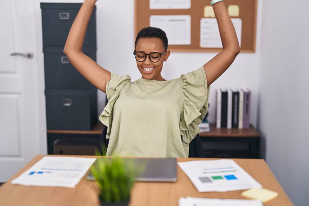 Africano americano mulher trabalhador de negócios usando laptop com expressão vencedora no escritório - Foto, Imagem