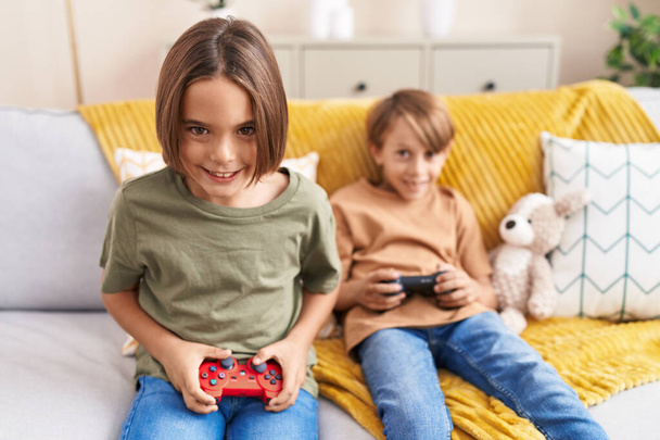Adorable boys playing video game sitting on sofa at home - Фото, изображение