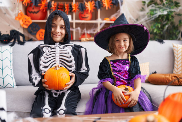 Чарівний хлопчик і дівчинка мають вечірку на Хеллоуїн тримає гарбуз вдома
 - Фото, зображення