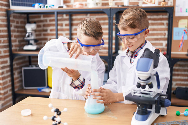 Imádnivaló fiúk diák öntés folyadék kémcső laboratóriumi osztályteremben - Fotó, kép