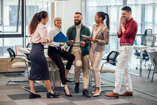 A business team is standing in a modern office and having a discussion. Group of multiethnic business people working together in the office - Foto, Imagem